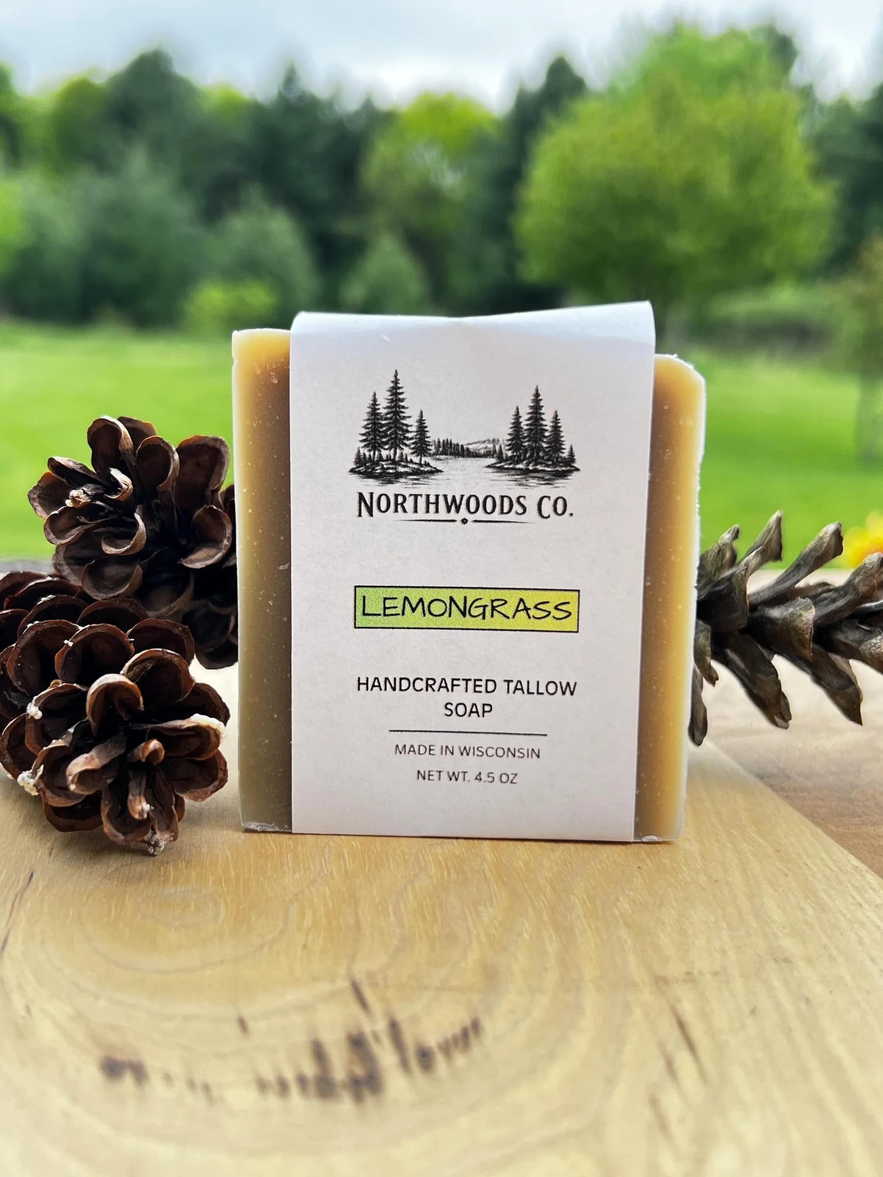 May include: A rectangular bar of lemongrass scented soap with a white label. The label reads "NORTHWOODS CO." and "LEMONGRASS HANDCRAFTED TALLOW SOAP MADE IN WISCONSIN NET WT. 4.5 OZ." The soap is on