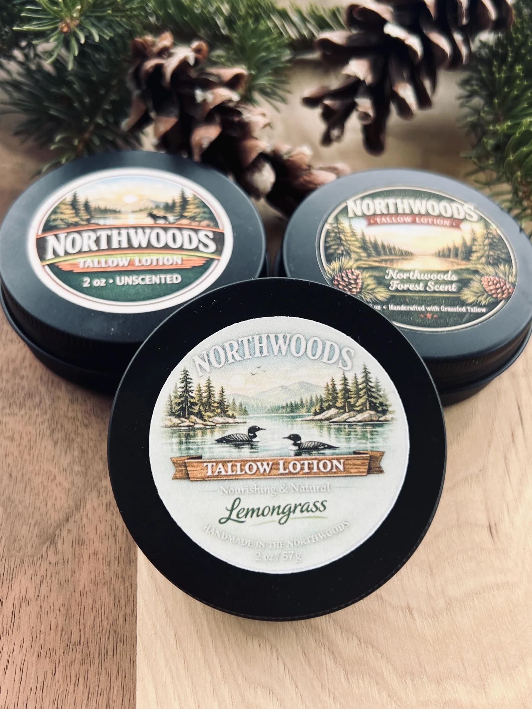 May include: Three black tins of Northwoods Tallow Lotion. One tin is labeled "Unscented", another "Forest Scent", and the third "Lemongrass". Each tin has a nature-themed label with illustrations of